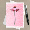 Greeting card with pink flower design on a pink polka dot background, pen on the side.