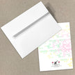White envelope and card with colorful geometric pattern on a beige background