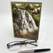 Greeting card with a waterfall design, glasses, and a pen on a white background