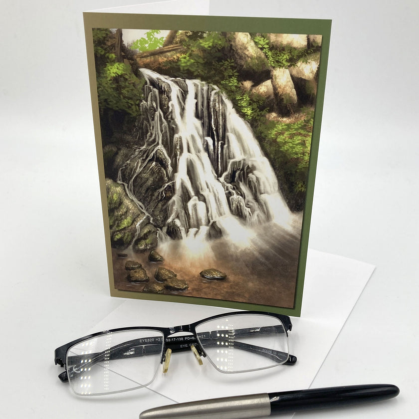Greeting card with a waterfall design, glasses, and a pen on a white background