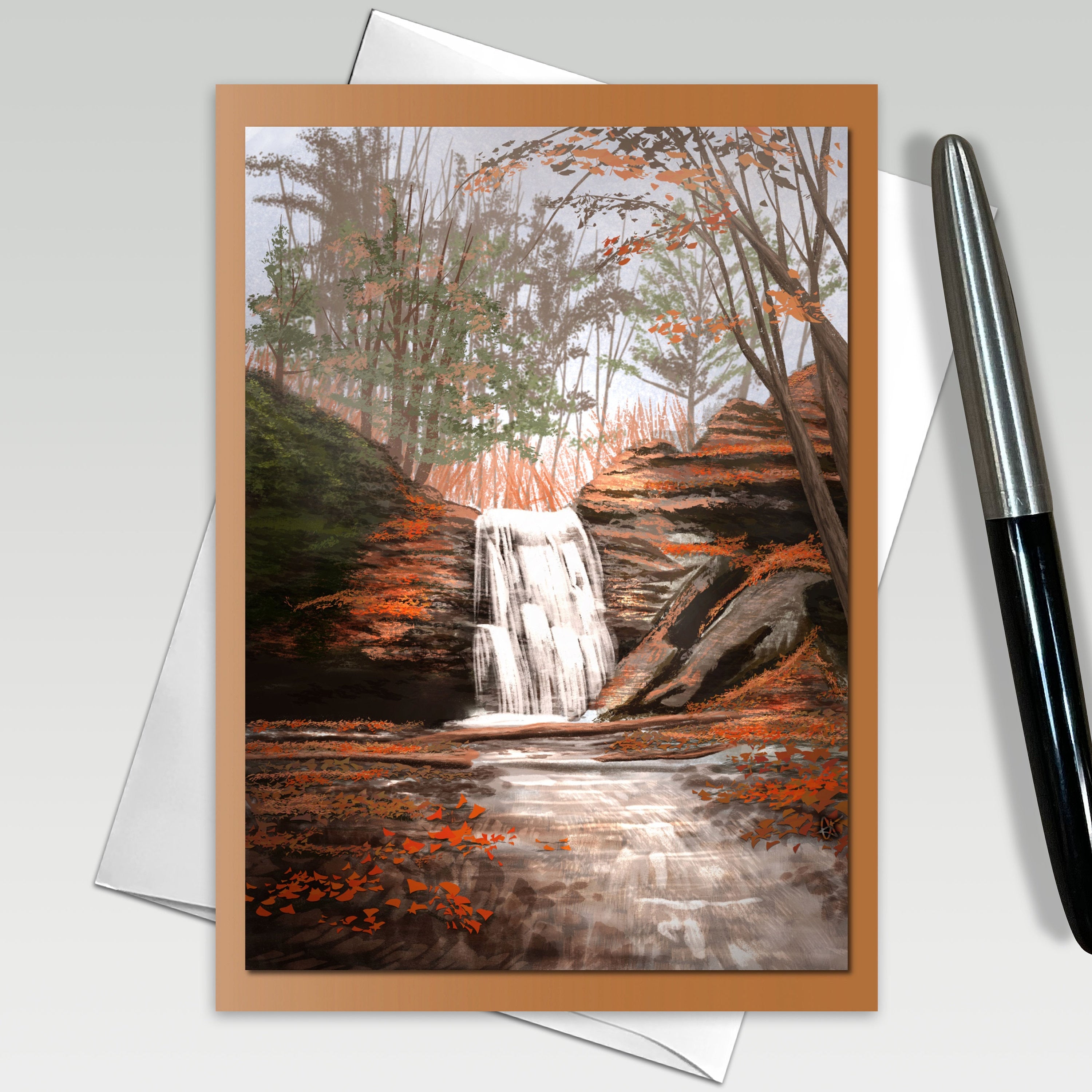 Greeting card with a watercolor painting of a forest scene with a waterfall, pen on the side.