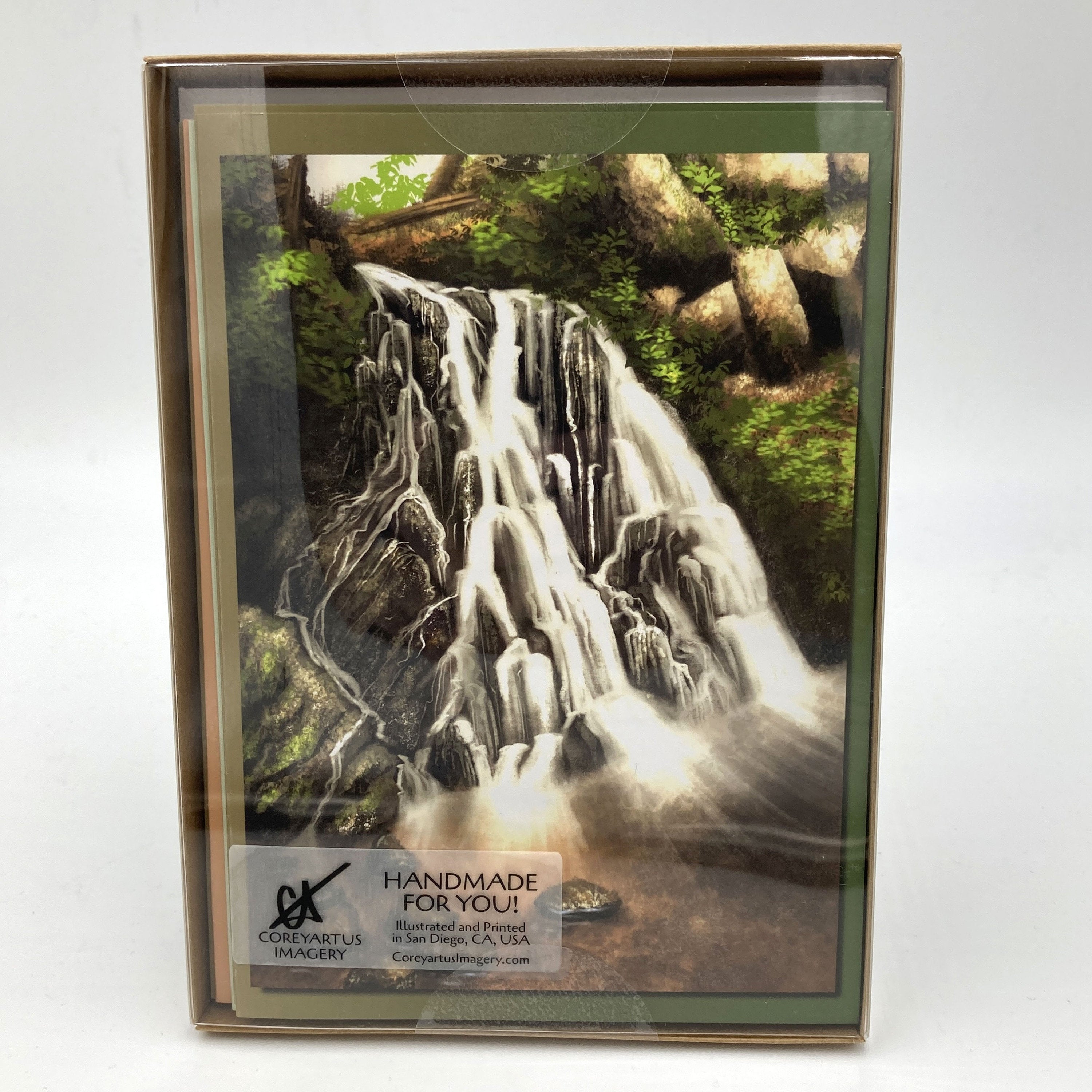 Package of greeting cards with top card featuring a waterfall with trees and greenery on a white background