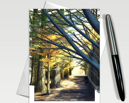 Greeting card with a scenic view of a tree-lined path, pen on the side.