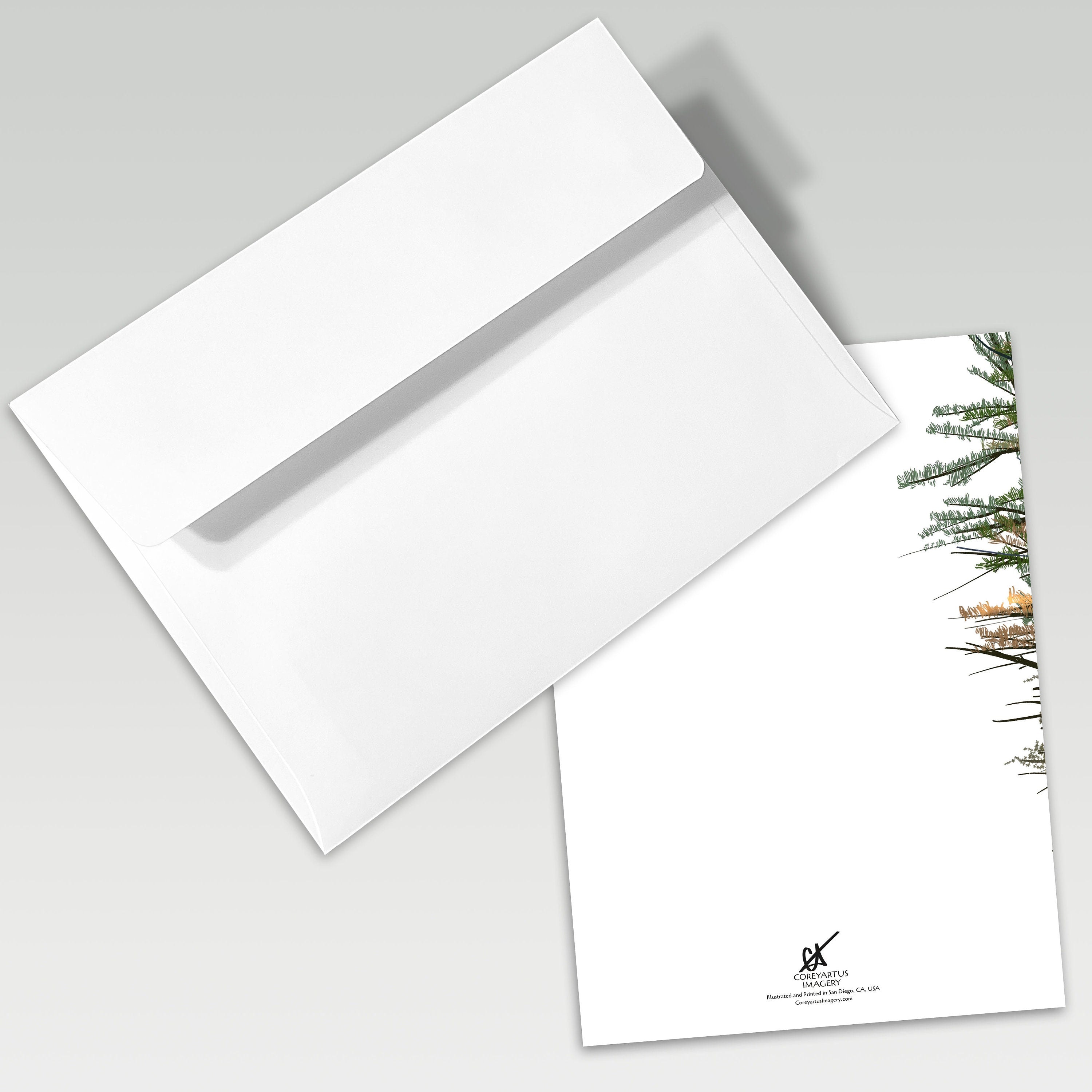 White envelope and card with a snowy tree design on a gray background