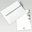 White envelope and card with a snowy tree design on a gray background