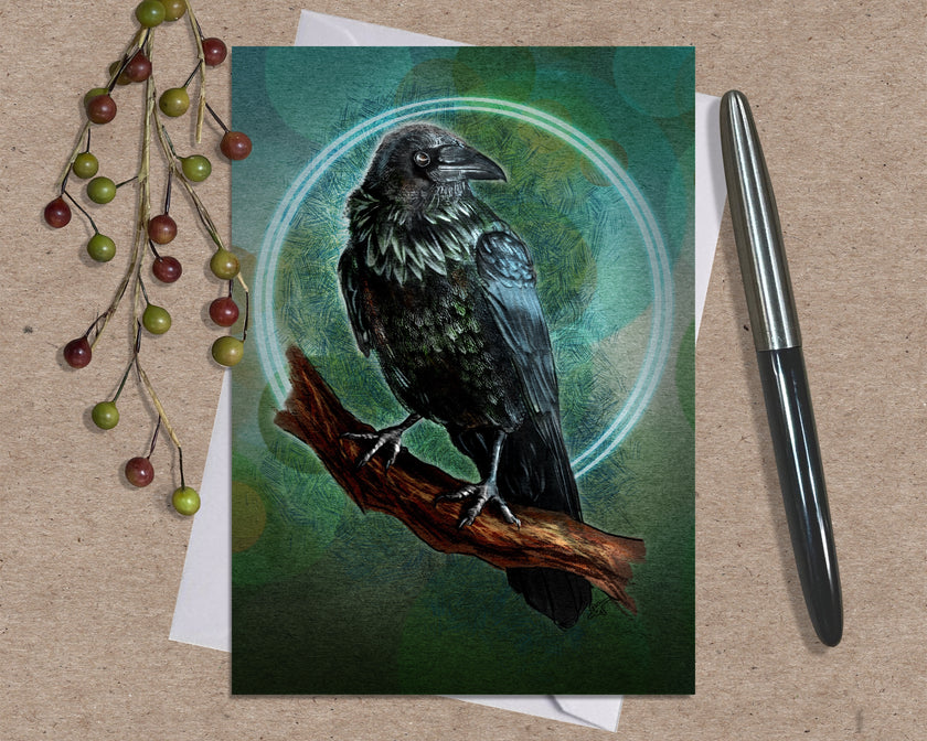 Greeting card with a raven illustration on a wooden surface with a pen and decorative branches.