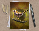 Greeting card with a bird illustration on a textured surface with a pen and dried plants.