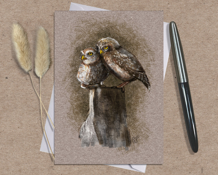 Greeting card with owl illustration on a textured surface with a pen and dried plants.
