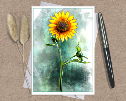 A square art print featuring a vibrant yellow sunflower with a textured teal and green watercolor background, styled on a brown kraft paper surface with a black pen and dried bunny tail grass.