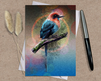 Greeting card with a colorful bird illustration on a textured surface with a pen and dried plants.