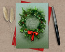 Christmas card with green wreath and red bow on a beige background