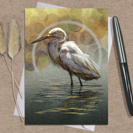 Greeting card with a egret design on a textured surface with a pen and dried plants.