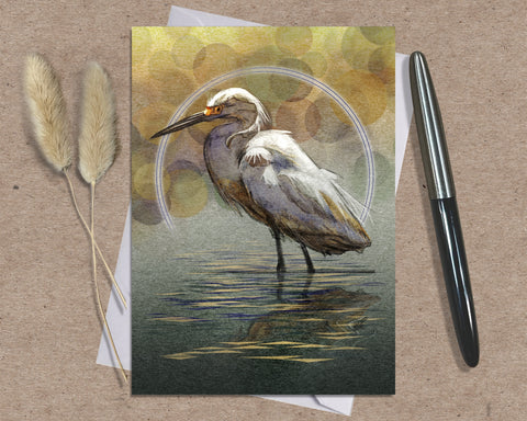 Greeting card with a egret design on a textured surface with a pen and dried plants.