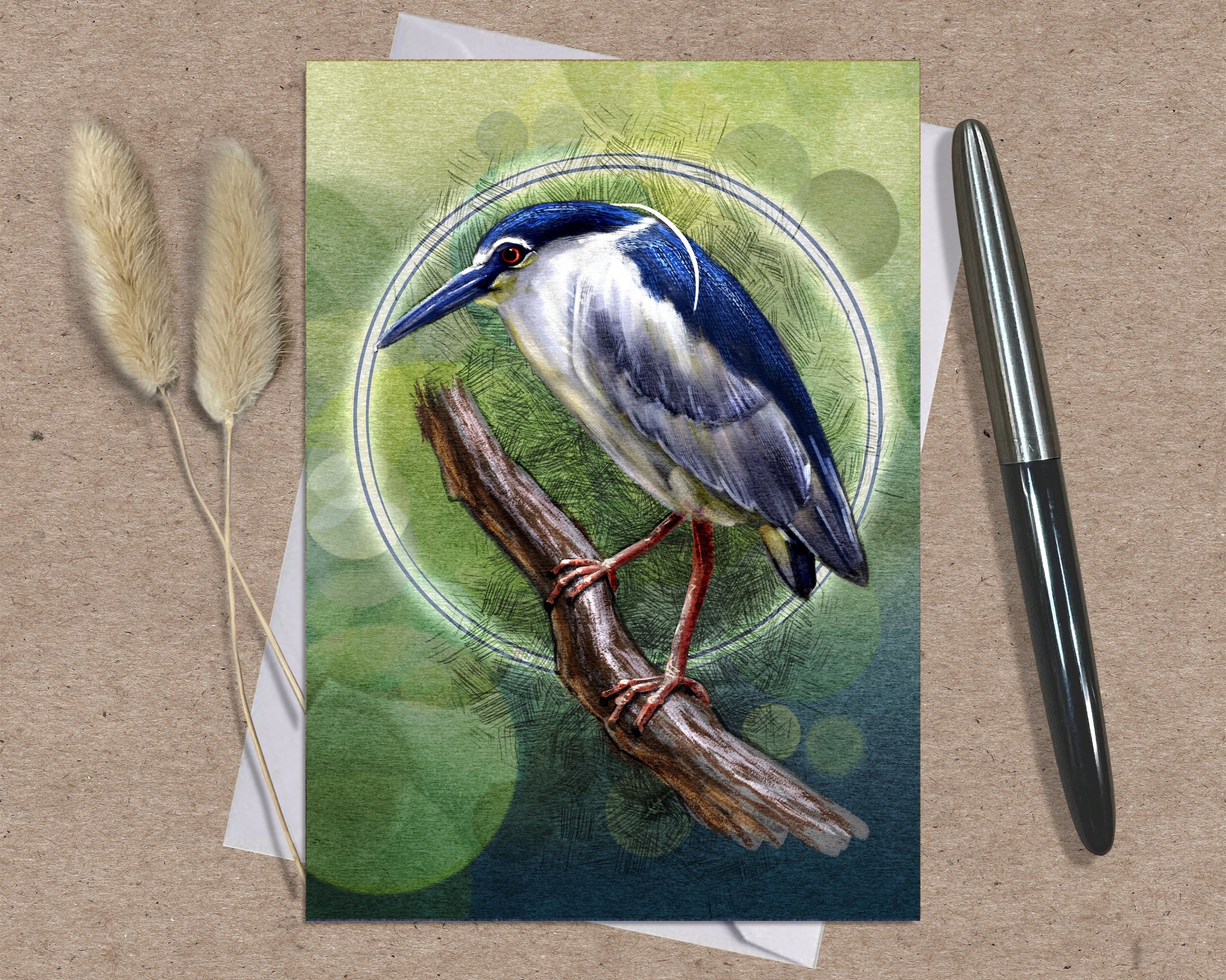 Greeting card with a bird illustration on a wooden surface with a pen and dried plants.