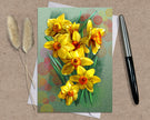 Greeting card with yellow flowers on a textured surface with a pen and dried plants.