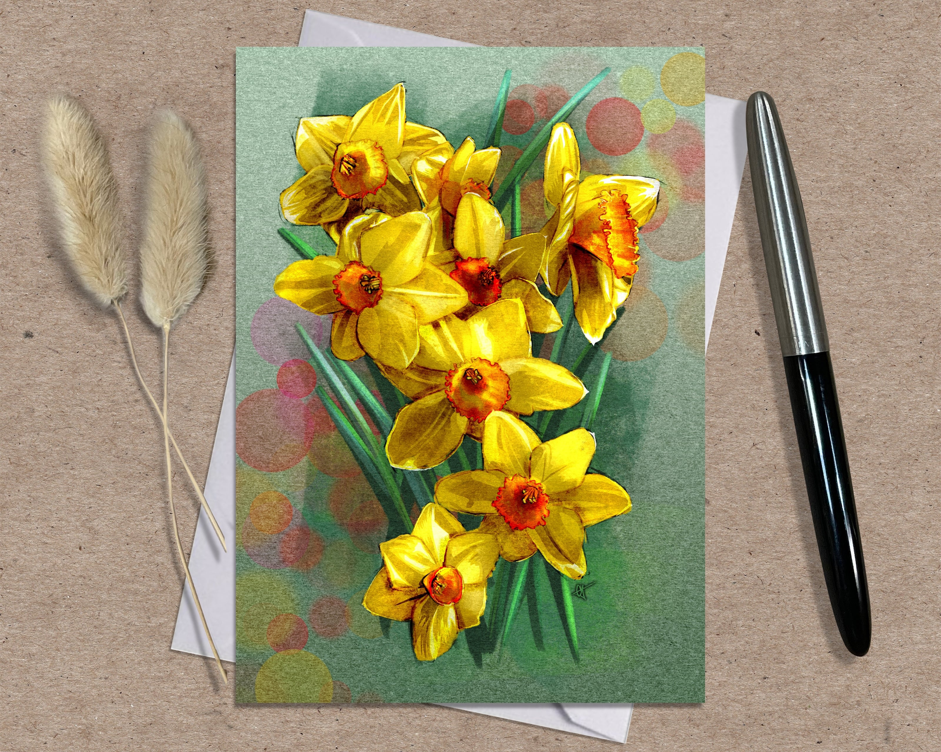 Greeting card with yellow flowers on a textured surface with a pen and dried plants.