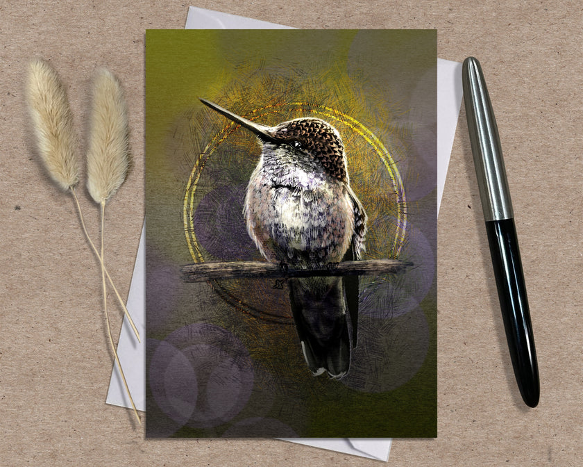 Greeting card with a hummingbird illustration on a textured surface with a pen and dried plants.