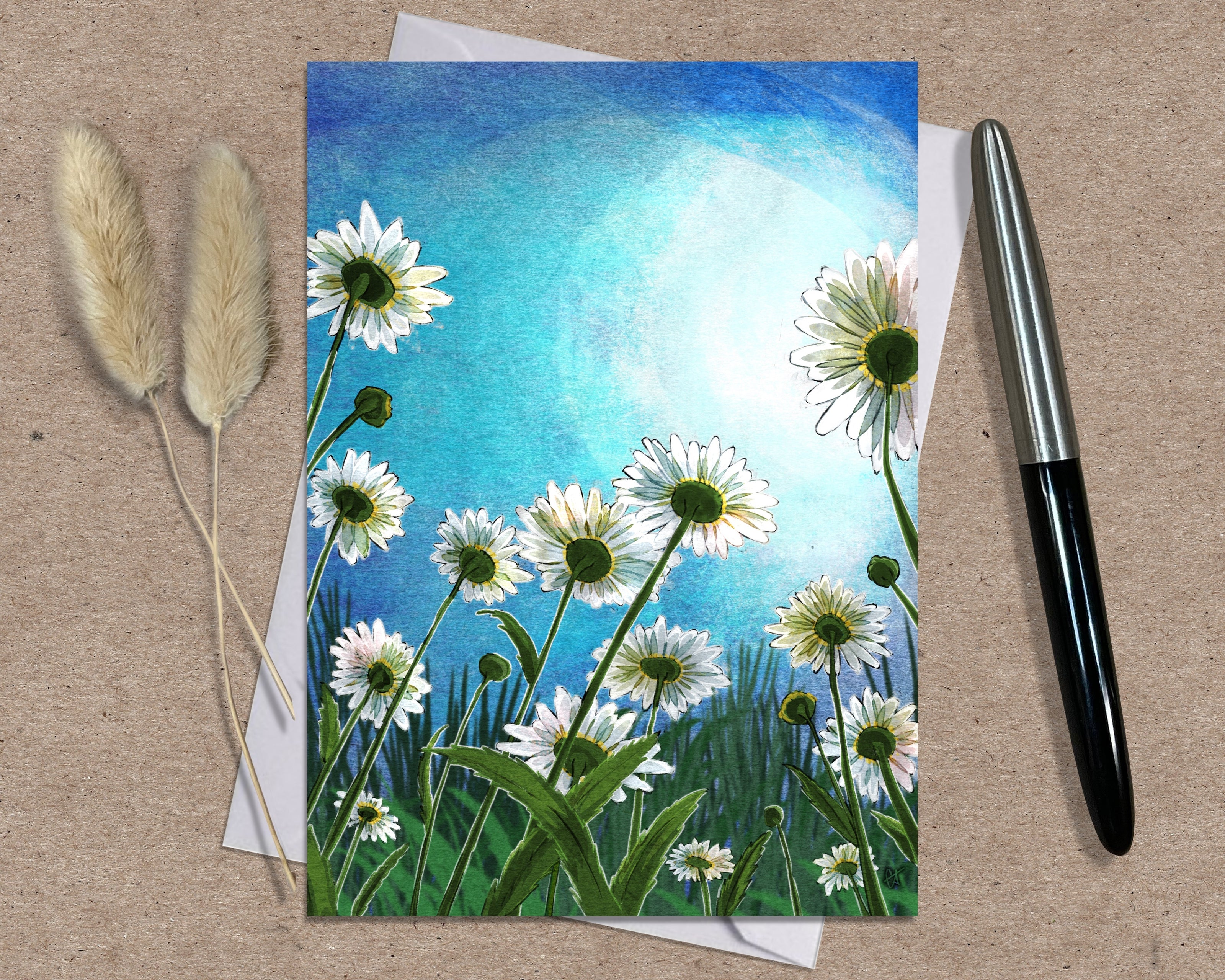 Greeting card with floral design on a textured surface with a pen and dried plants.