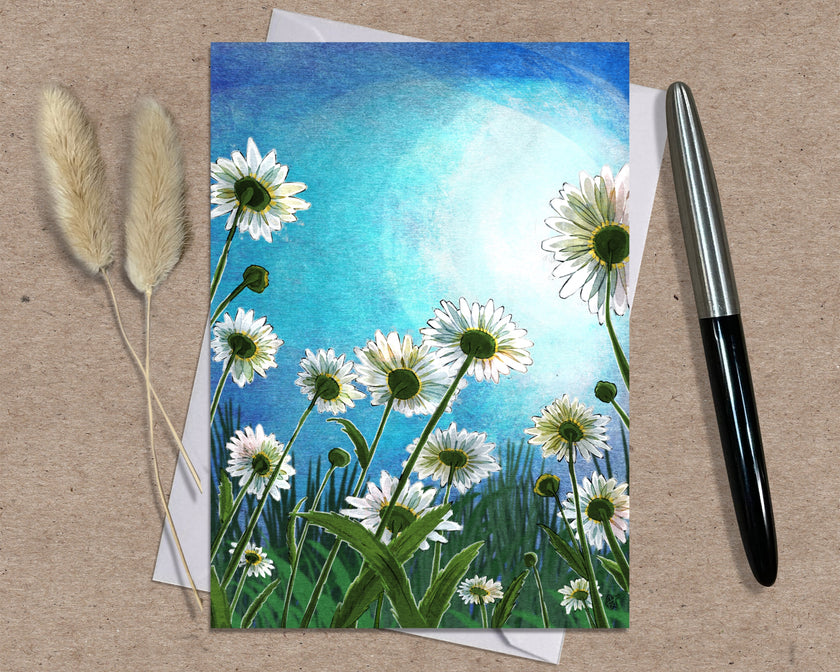 Greeting card with floral design on a textured surface with a pen and dried plants.