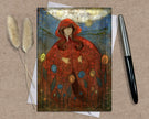 Greeting card with a red hooded figure on a textured surface with a pen and dried plants.