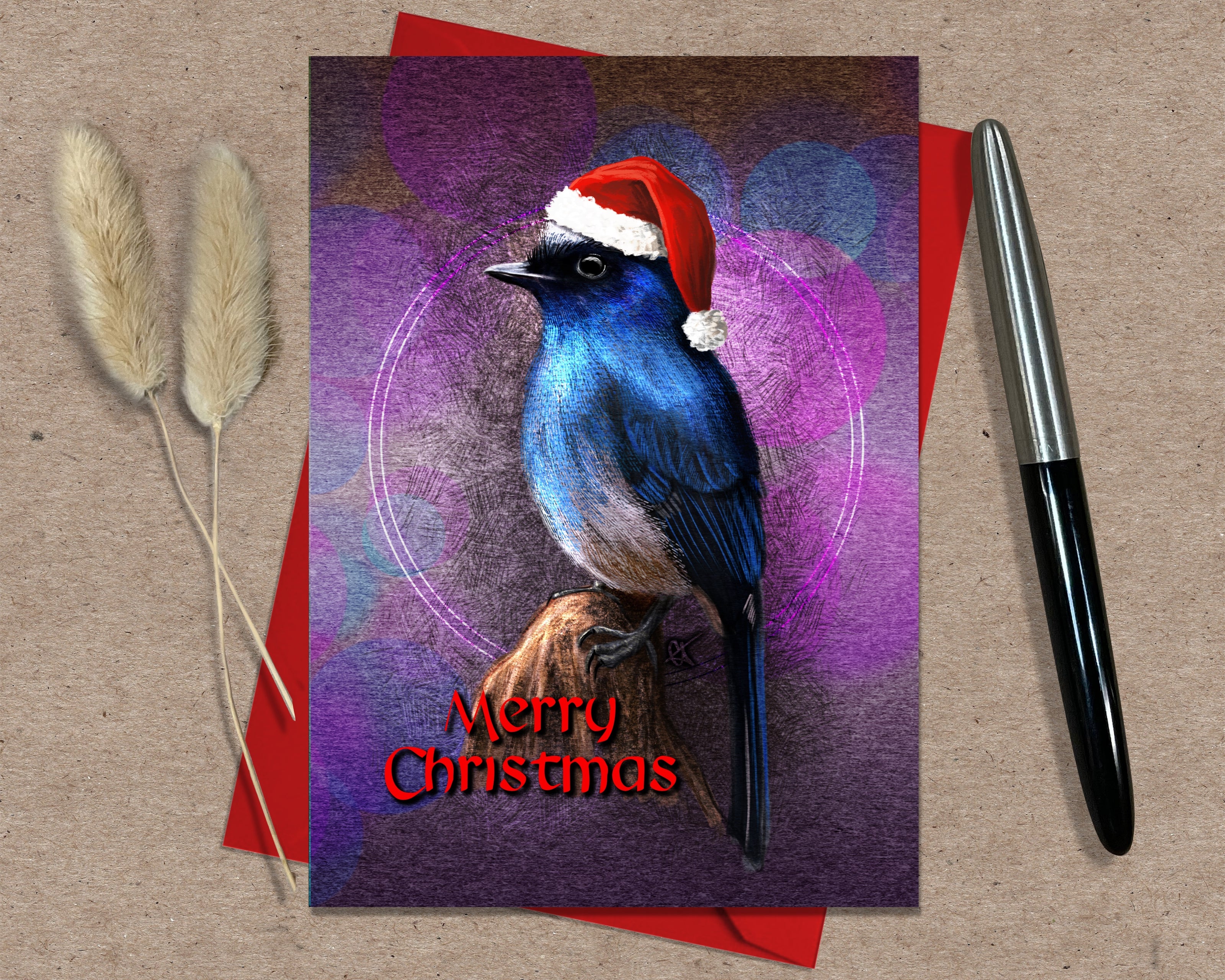Christmas card with a blue bird wearing a Santa hat on a red envelope.