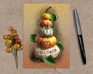 Halloween-themed card with pumpkins and berries on a textured surface with a pen.