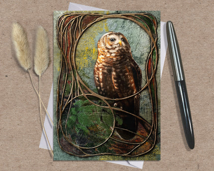 Greeting card with an owl design on a textured surface with a pen and dried plants.