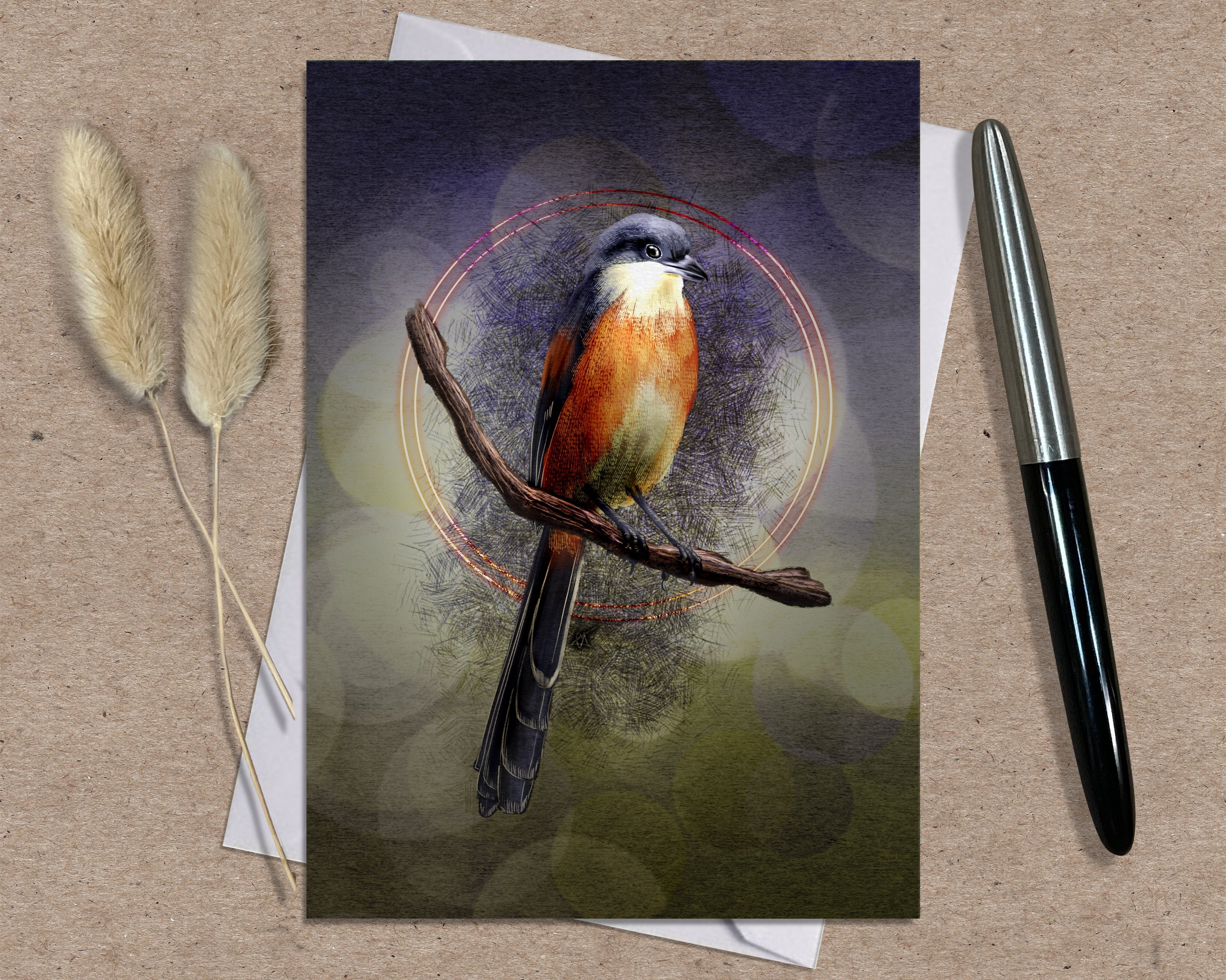 Greeting card with a bird illustration on a branch, placed on a textured surface with a pen and dried plants.