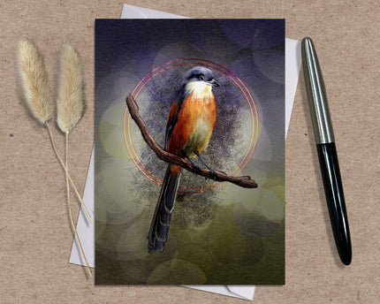 Greeting card with a bird illustration on a branch, placed on a textured surface with a pen and dried plants.