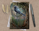 Greeting card with a bird illustration on a textured surface with a pen and dried plants.