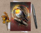 Card with a robin design on a textured surface with a pen and decorative branch.