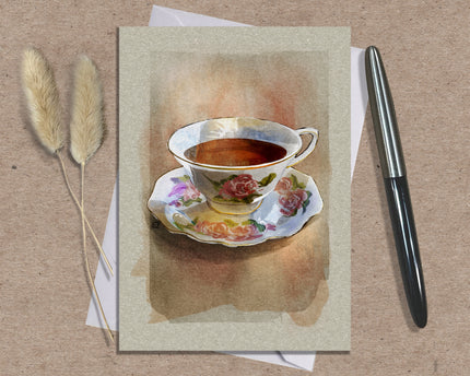Greeting card with a floral teacup design on a textured surface with a pen and dried plants.