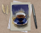 Card with a painting of a blue teacup and saucer on a textured surface with a pen and dried plants.