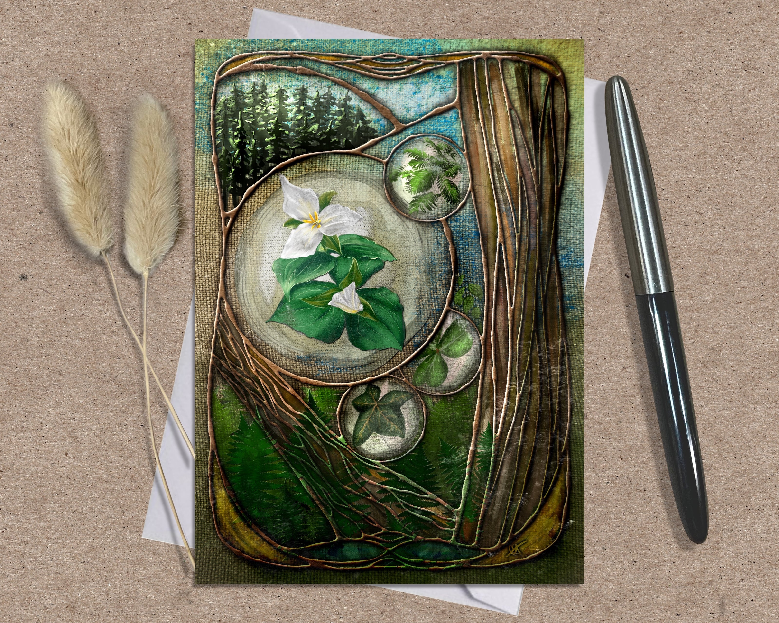 Decorative card with floral design on a textured surface with a pen and dried plants.