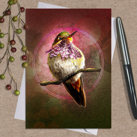 Greeting card with a hummingbird design on a textured surface with a pen and decorative elements.