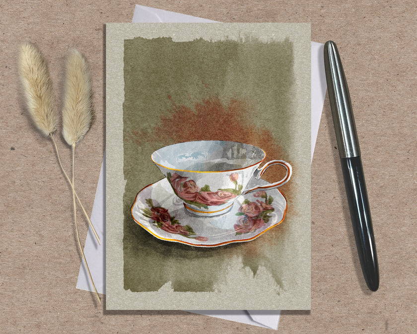 Greeting card with a teacup design on a textured surface with a pen and dried plants.