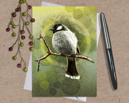Card with a bird illustration on a branch, surrounded by greenery and a pen on a textured surface.