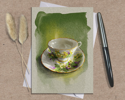 Greeting card with a teacup design on a textured surface with a pen and dried plants.