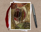 Decorative greeting card with abstract design on a textured surface with a pen and feather.