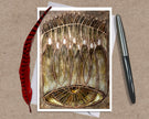 Greeting card with intricate design on a brown background with a pen and feather.