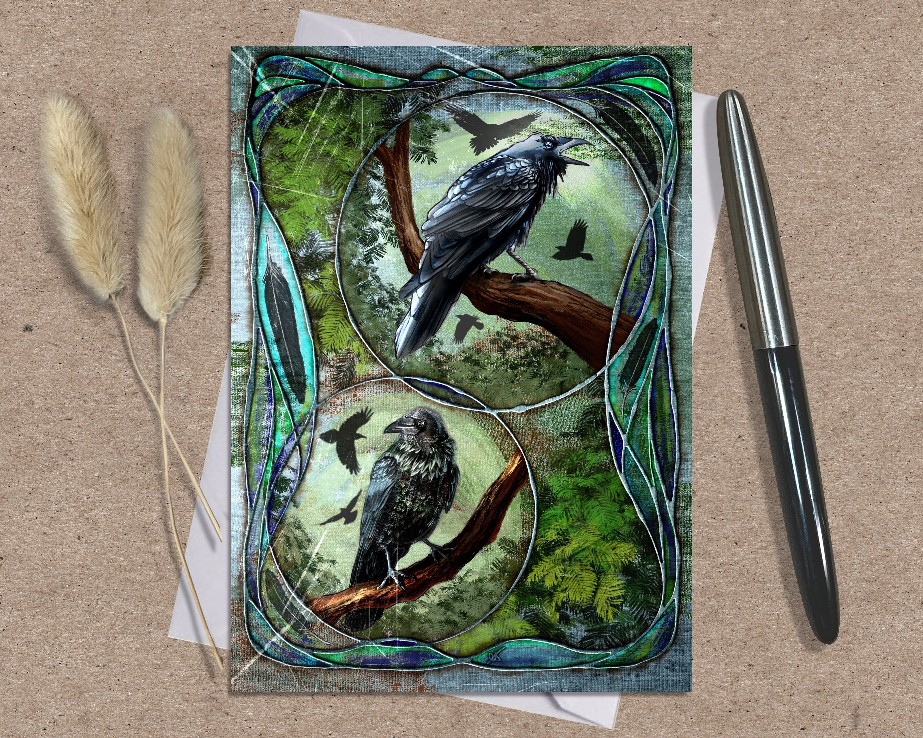 Decorative card with crow illustrations on a textured surface with a pen and dried plants.