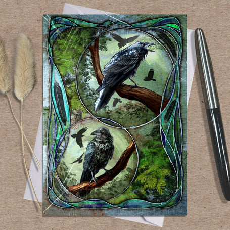Decorative card with crow illustrations on a textured surface with a pen and dried plants.