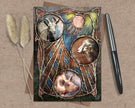 Decorative card with animal illustrations on a textured surface with a pen and dried plants.