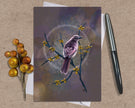 Greeting card with a bird illustration on a textured surface with a pen and decorative branch.