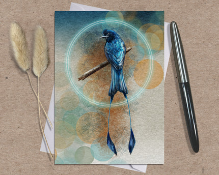 Greeting card with a blue bird illustration on a textured surface with a pen and dried plants.