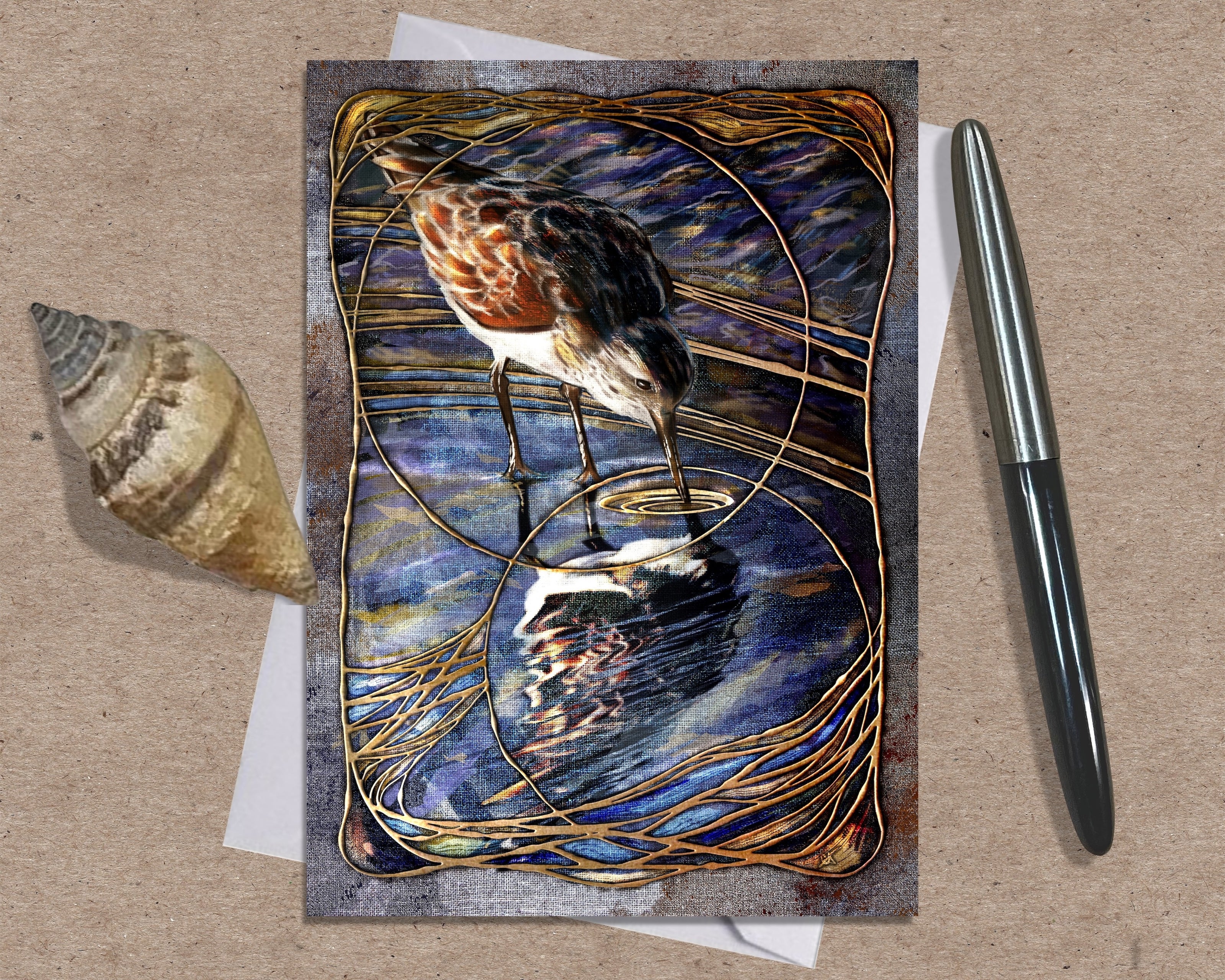 Greeting card with a bird design on a textured surface with a shell and pen.