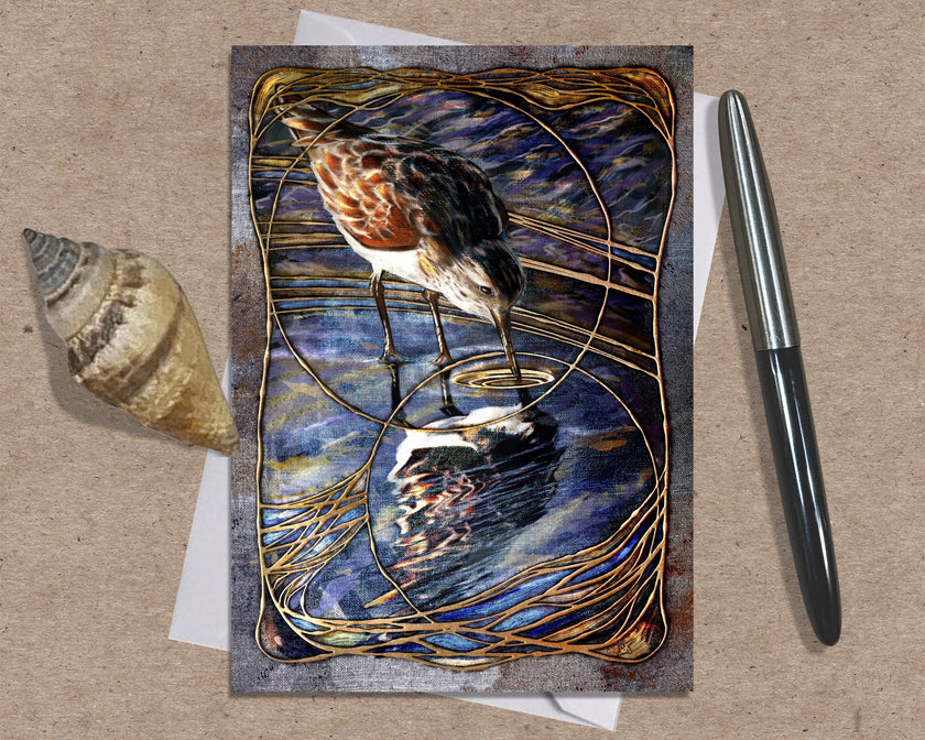 Greeting card with a bird design on a textured surface with a shell and pen.