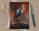 Greeting card with a heron design on a textured surface with a pen and dried plants.