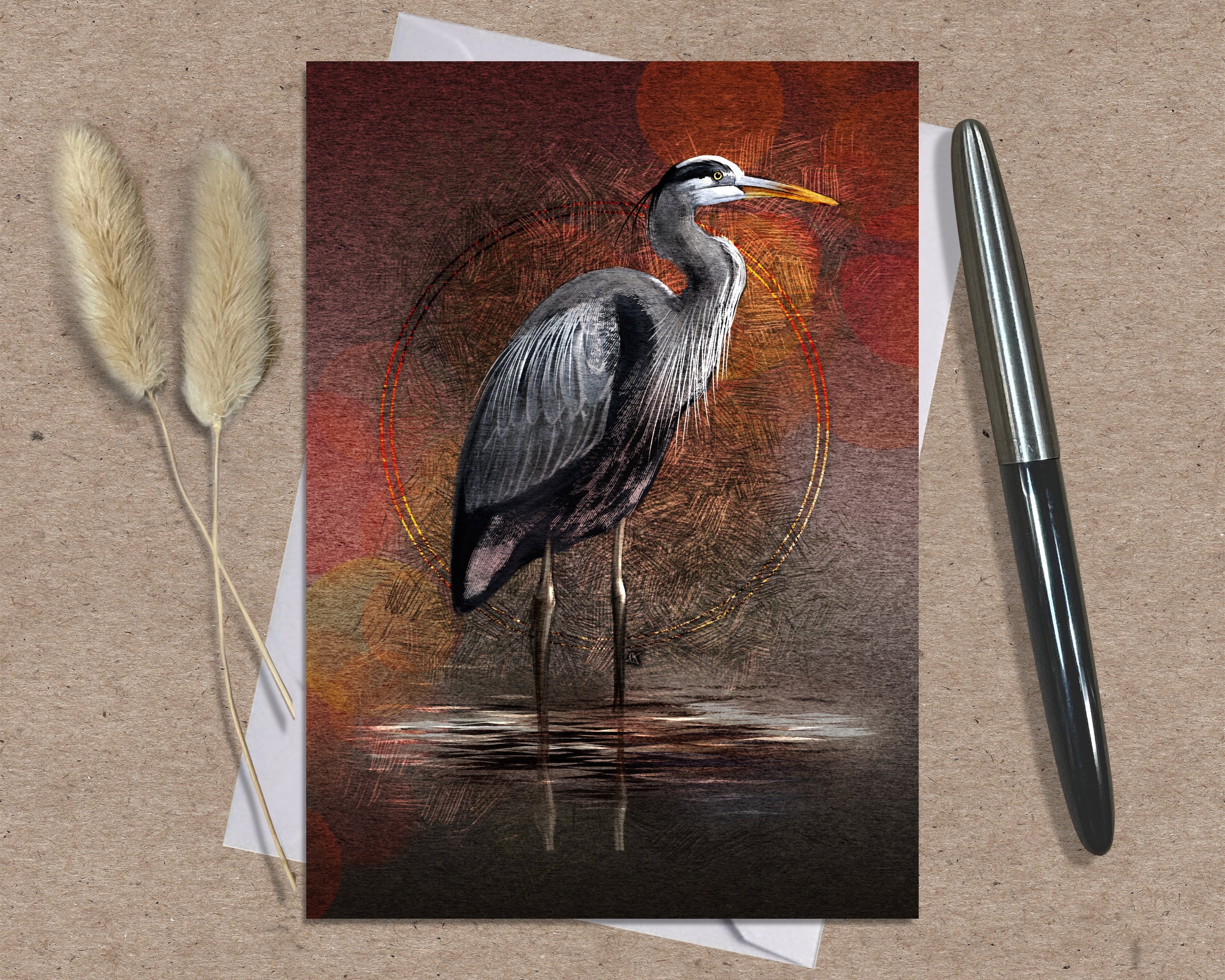 Greeting card with a heron design on a textured surface with a pen and dried plants.