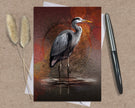 Greeting card with a heron design on a textured surface with a pen and dried plants.